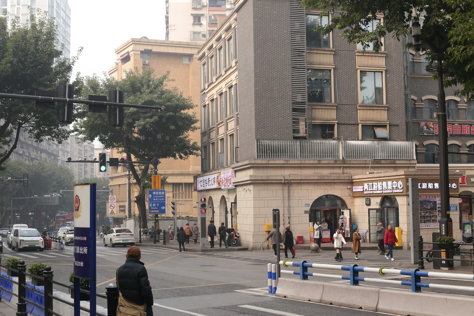 Pessoas atravessando uma rua movimentada entre edifícios e tráfego urbano