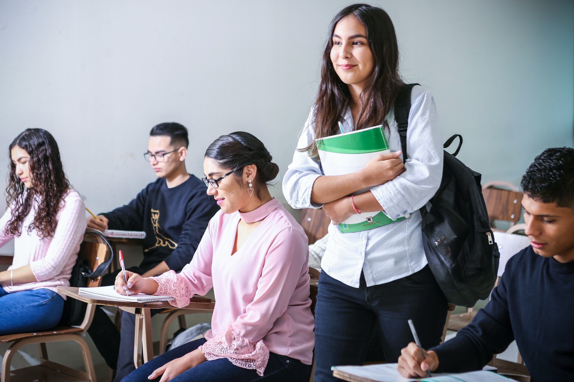 Estudantes acompanhando uma aula em uma sala iluminada